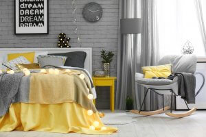 A bedroom with yellow pillows and blankets, contrasted with greys