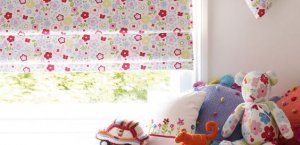 Floral print blinds half rolled up in a window in a child's bedroom.