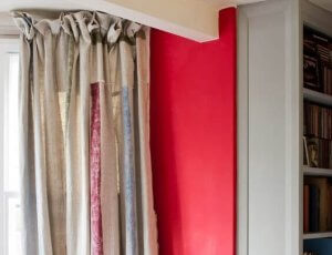 Curtains made out of a canvas material, bunched up in the edge of a wall.