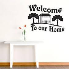 You can use decals to decorate an entryway, in this case, one that says "Welcome to our home," with a house and trees.