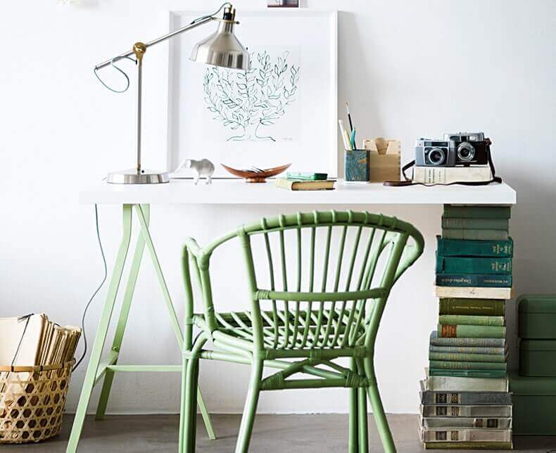 An IKEA desk with a stack of books as a support on one side
