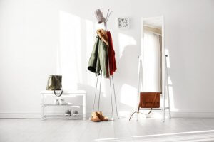 A picture shows an entryway painted white, with nothing but a shoe rack, a mirror, and a coat rack, and lots of empty space.