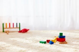 A picture shows a carpeted floor with some toy blocks laying on it, in a toy library.