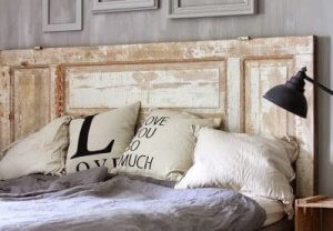 A reclaimed door is sitting behind a bed and acting as a headboard.