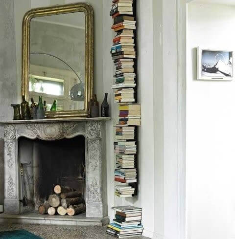 Stack of books on invisible shelves next to a fireplace