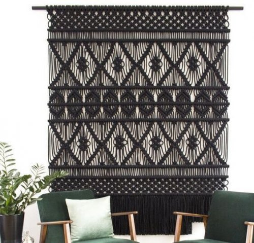 A large black macrame wall hanging in a turquoise themed decor