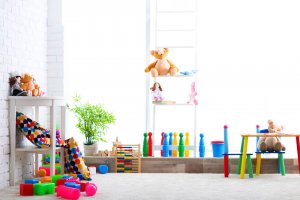A brightly lit toy library with well organized shelves and tables and lots of colorful toys.