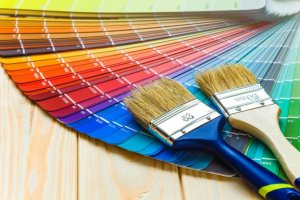 A pair of paint brushes is lying on top of a fanned out spread of paint swatches.