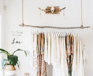 An eco-friendly clothes rack with light clothes hanging from it.