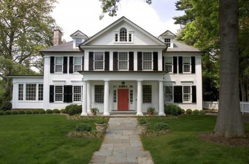 A white colonial house with a large yard.