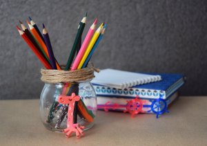 A glass jar containing colored pencils.