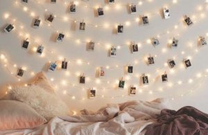 A photo mural is hanging on a wall along string lights.