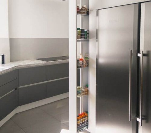 A spice rack that pulls out from the wall on wheels.