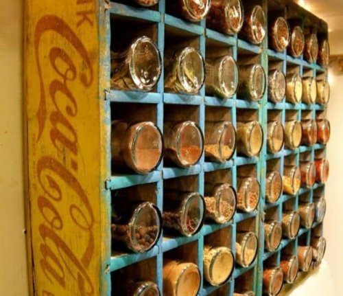 A spice rack made out of a wooden soda box.