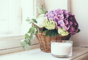 Candle and flowers on a windowsill.