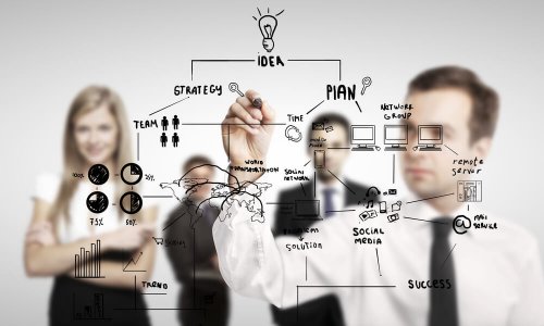 A man sketching on a bulletin board during a presentation.