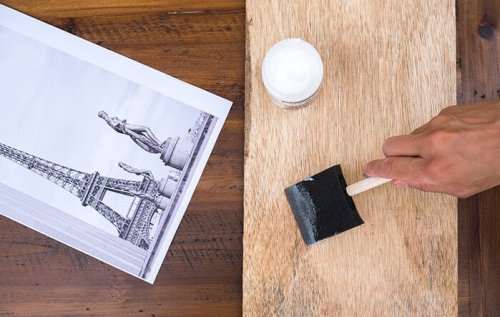A person applying gel to a piece of wood.