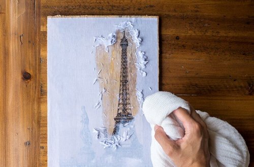 A person removing paper off the printed wood.