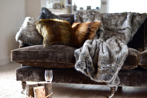A faux fur blanket on a grey couch.