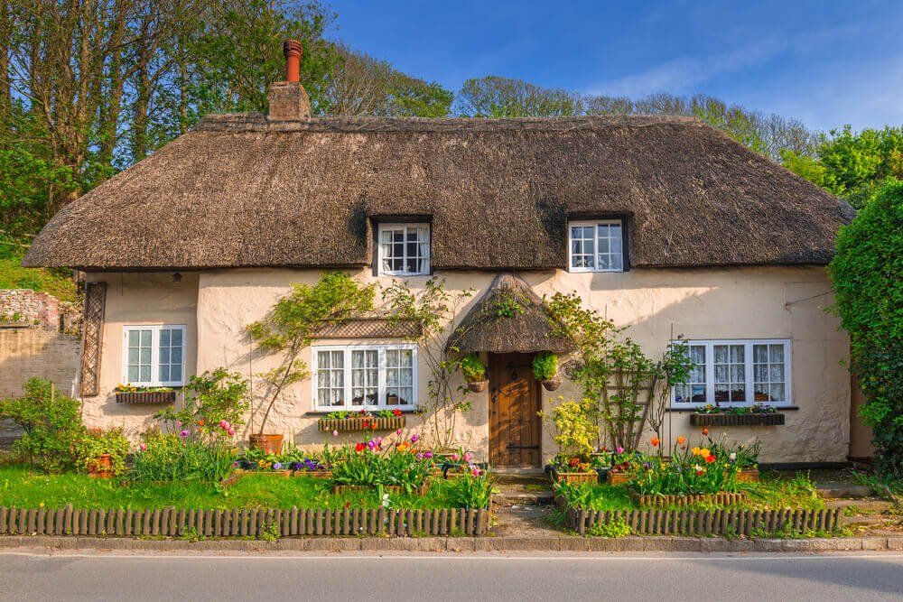 An English cottage with a thatched roof and climbing roses