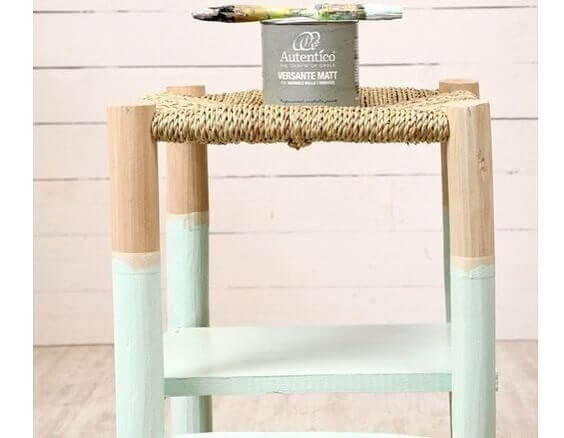 A painted timber stool with a natural fiber seat