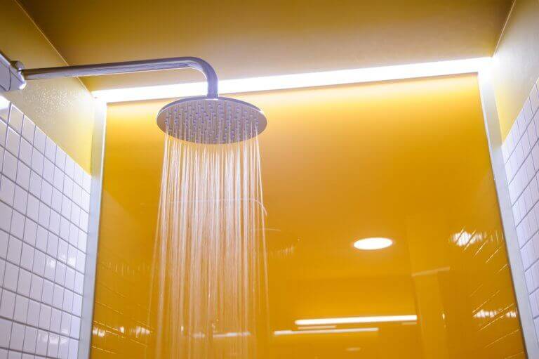 A dark mustard feature wall with white tiles in the shower