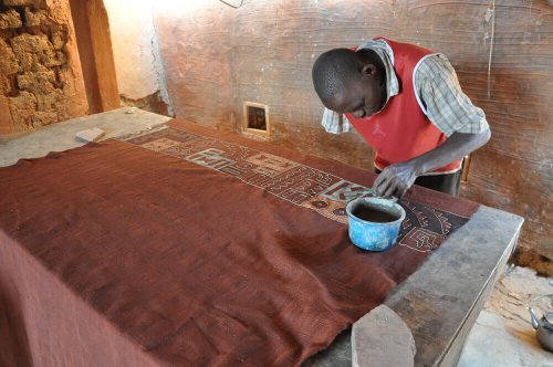 An man working on a roll of mud cloth.