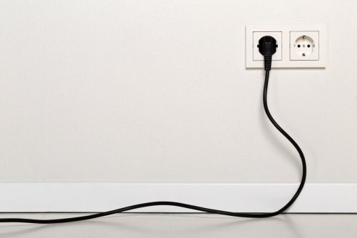 An electrical cable plugged into a wall.