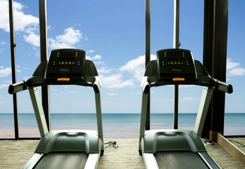 Two treadmills in a gym in front of the ocean.