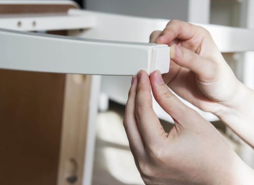 A person putting felt pads on the legs of a chair which can help prevent scratches on parquet floors.
