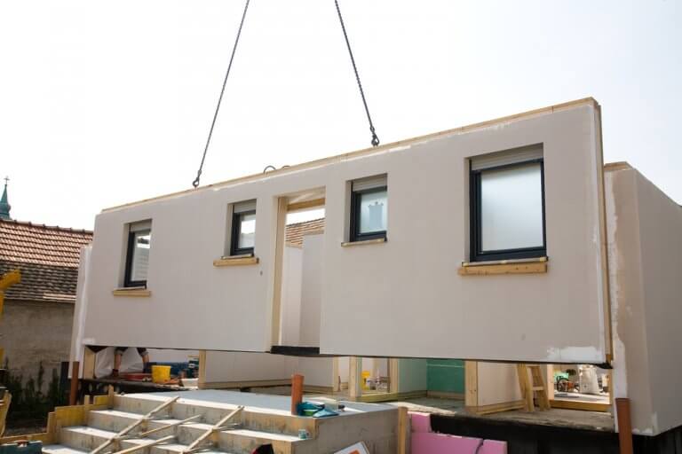 A completed wall is lifted into place for a modular home