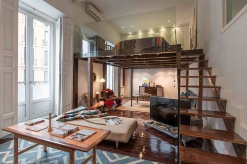 A small apartment with a high ceiling and a loft bedroom.