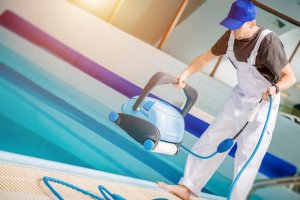 A man is holding a robot pool cleaner.