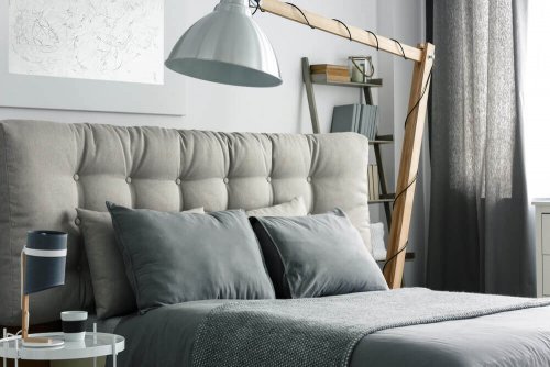 A large bed with gray headboard and linens