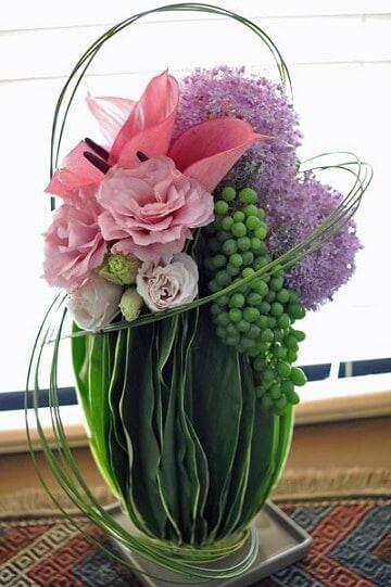 A flower arrangement with grapes.