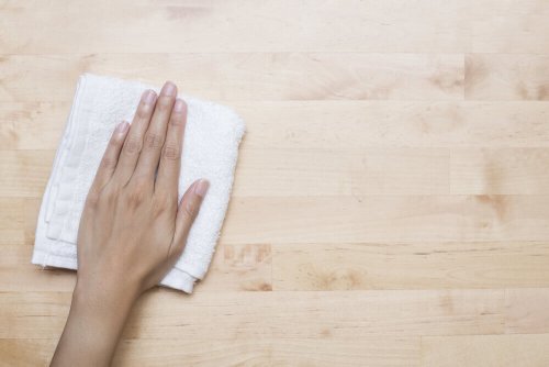 a hand clean a surface with a white cloth