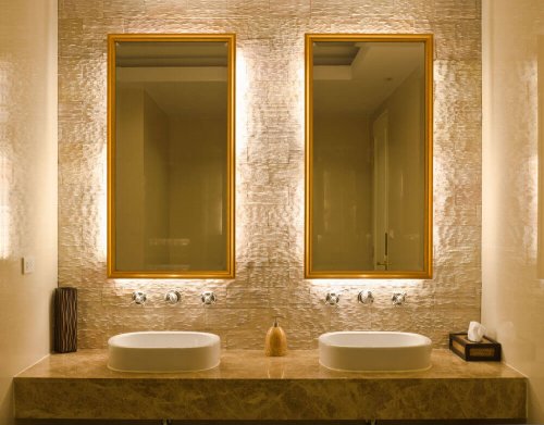 A gold bathroom with double mirrors.
