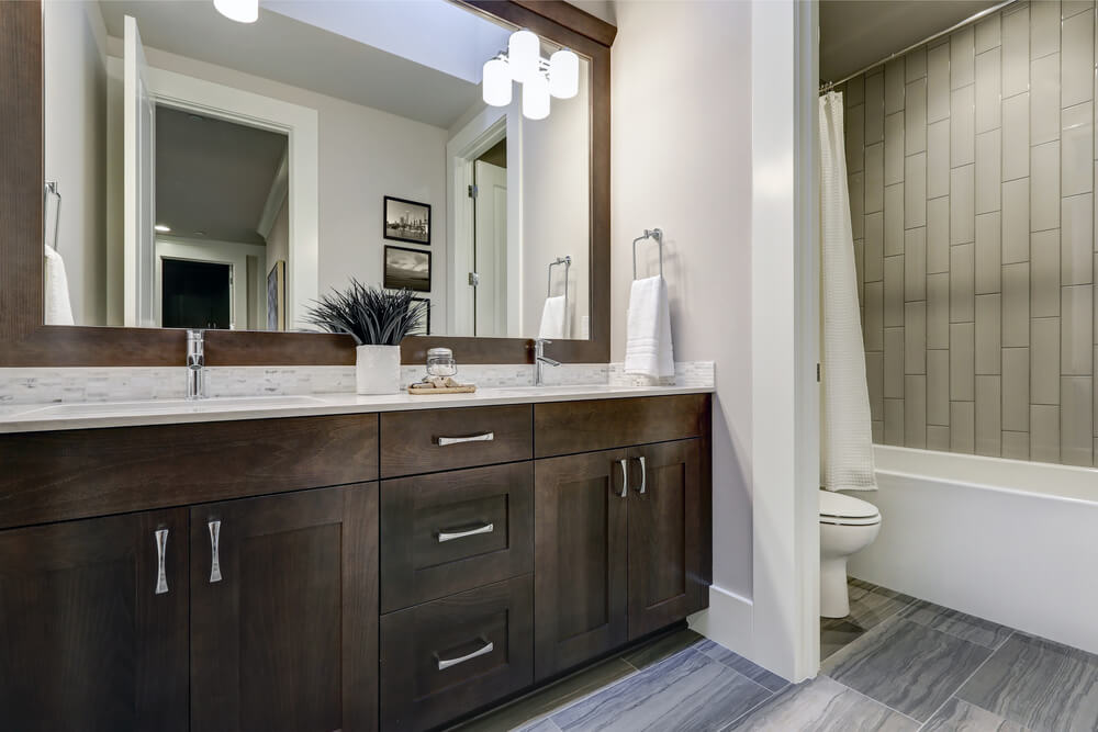 A large mirror in a gray and brown themed bathroom
