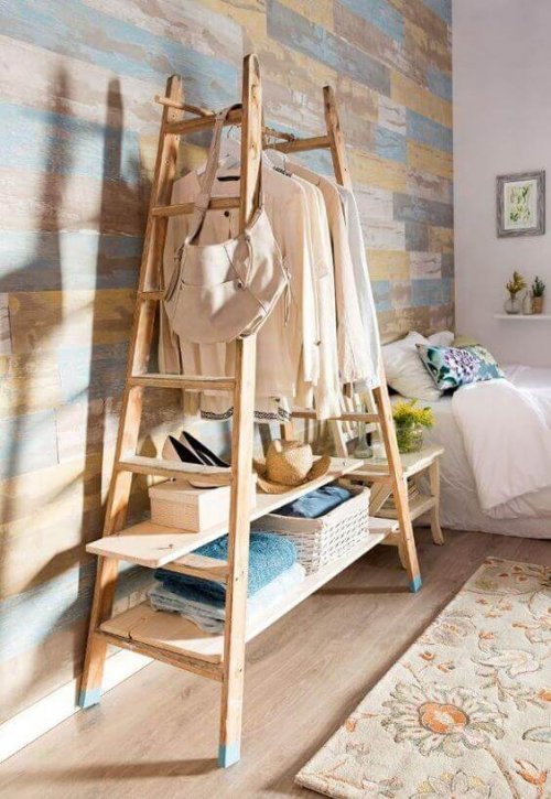 Clothes hanging from a wooden ladder in a dressing room.