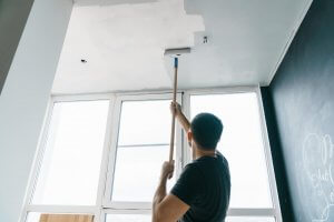 A man paints his ceiling.