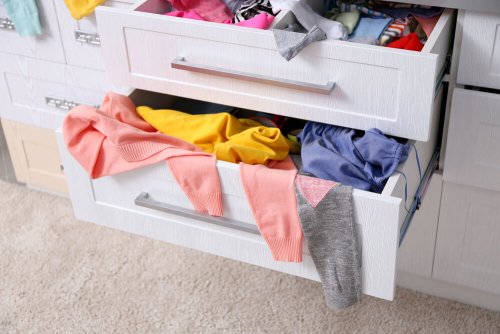 A dresser with clothes spilling out.