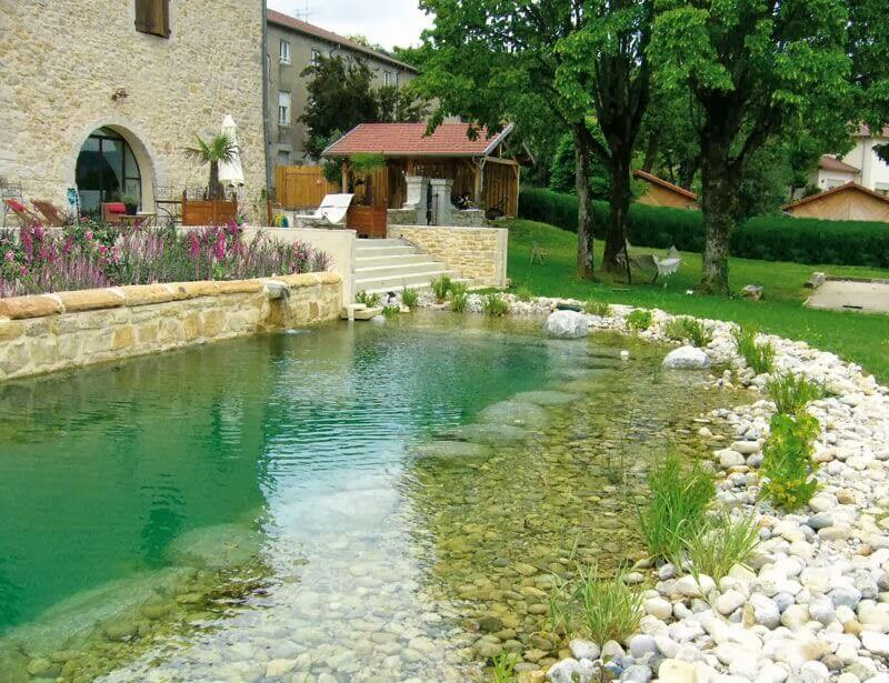 A natural swimming pool with pebbles and plants on the border