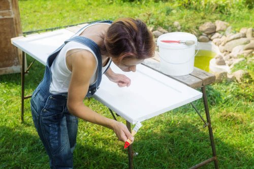 A woman painting a metal table.