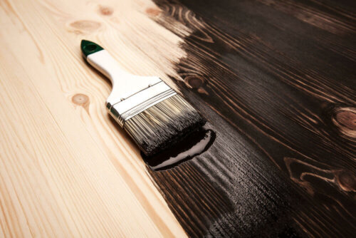 A brush with brown paint on top of a wooden surface.