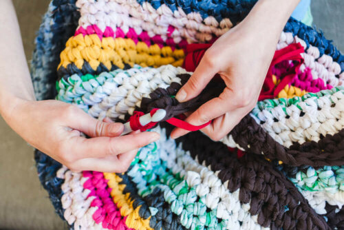 A person knitting a trapillo rug.