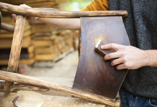 A person sanding a chair.