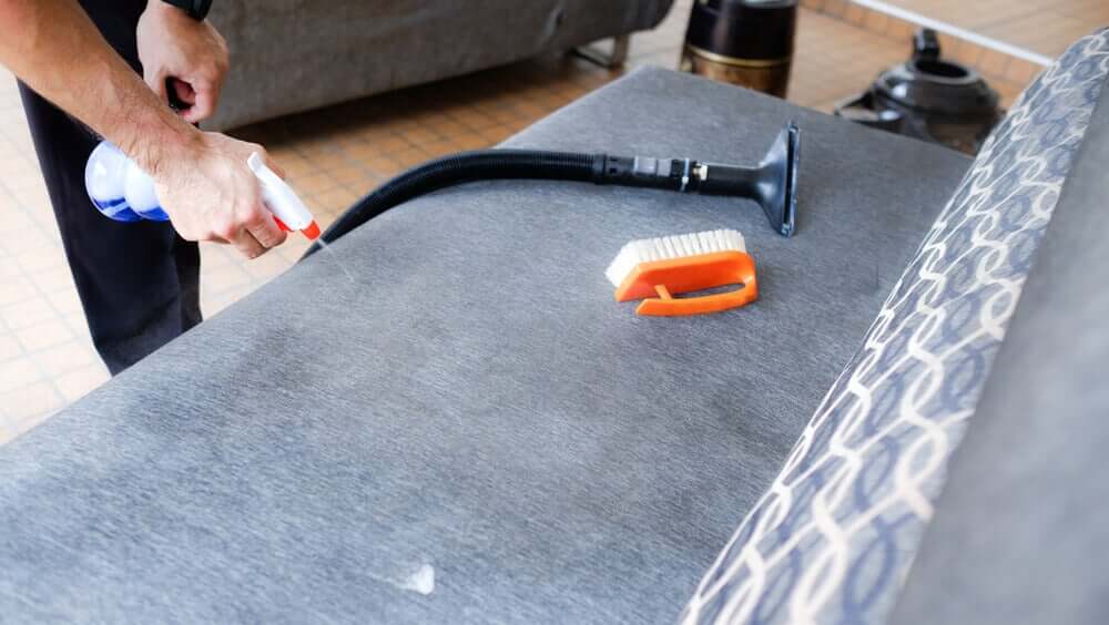 A man cleaning a sofa.
