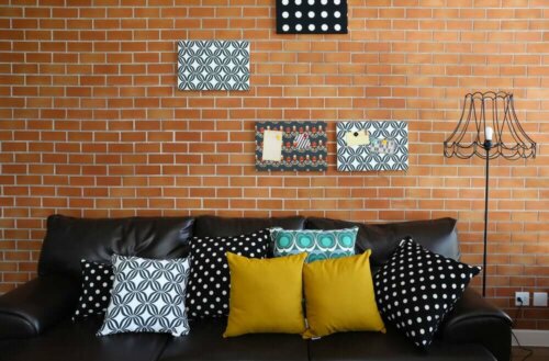 Room with a brick wall with black and other colors on the sofa