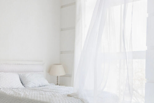 An all-white bedroom, one of the ten out-of-style decor trends.