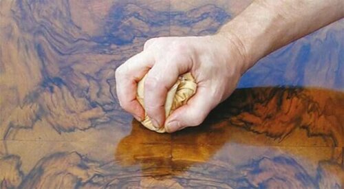Someone putting varnish on a table.